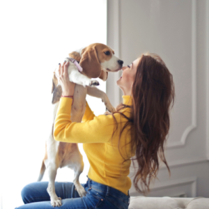 Brunette lady with yellow sweater holding a dog 